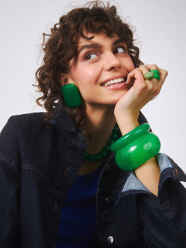 Kwadratowe kolczyki o intensywnie zielonym kolorze w połączeniu z inną biżuterią marki Berries