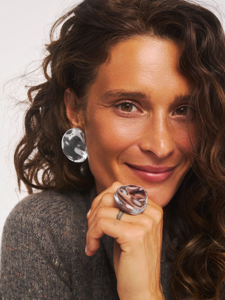  Duży pierścionek Oyster wykonany z żywicy o gładkiej, lustrzanej powierzchni i organicznej, obłej formie w secie z kolczykami z tej samej kolekcji 