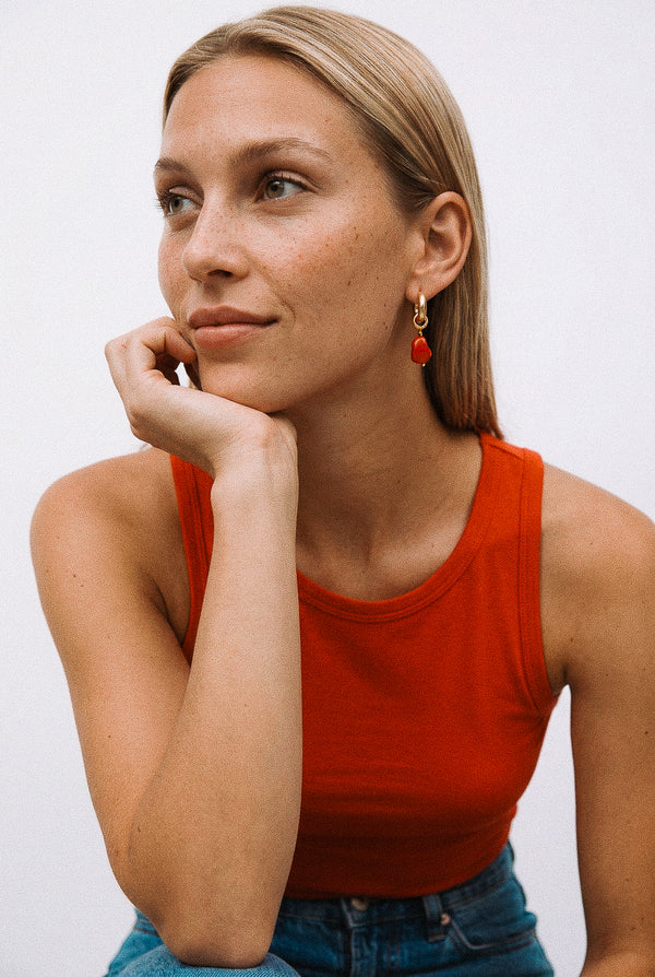 Pozłacane kolczyki z czerwoną zawieszką z żywicy na modelce.