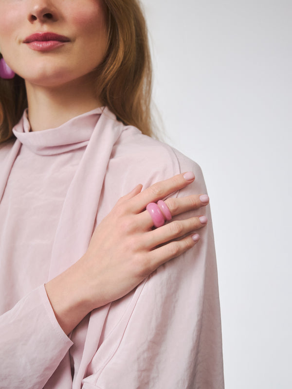 Modelka w różowej stylizacji nosząca dwa pierścionki marki Berries