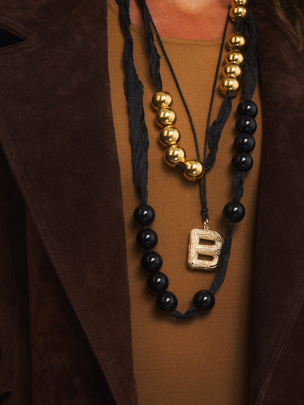 Złote korale z żywicy na czarnej wstążce w kolekcji Splash w zestawie z czarną ich wersją i naszyjnikiem z literką B